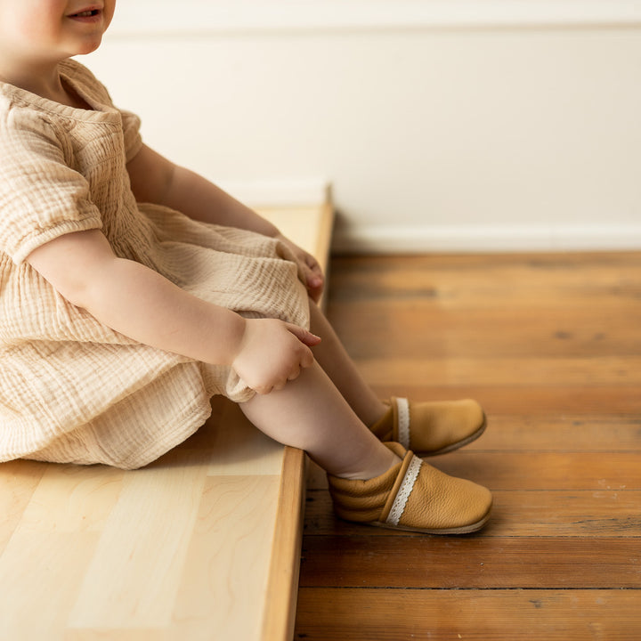 toddler girl wearing light brown leather slip-on moccs